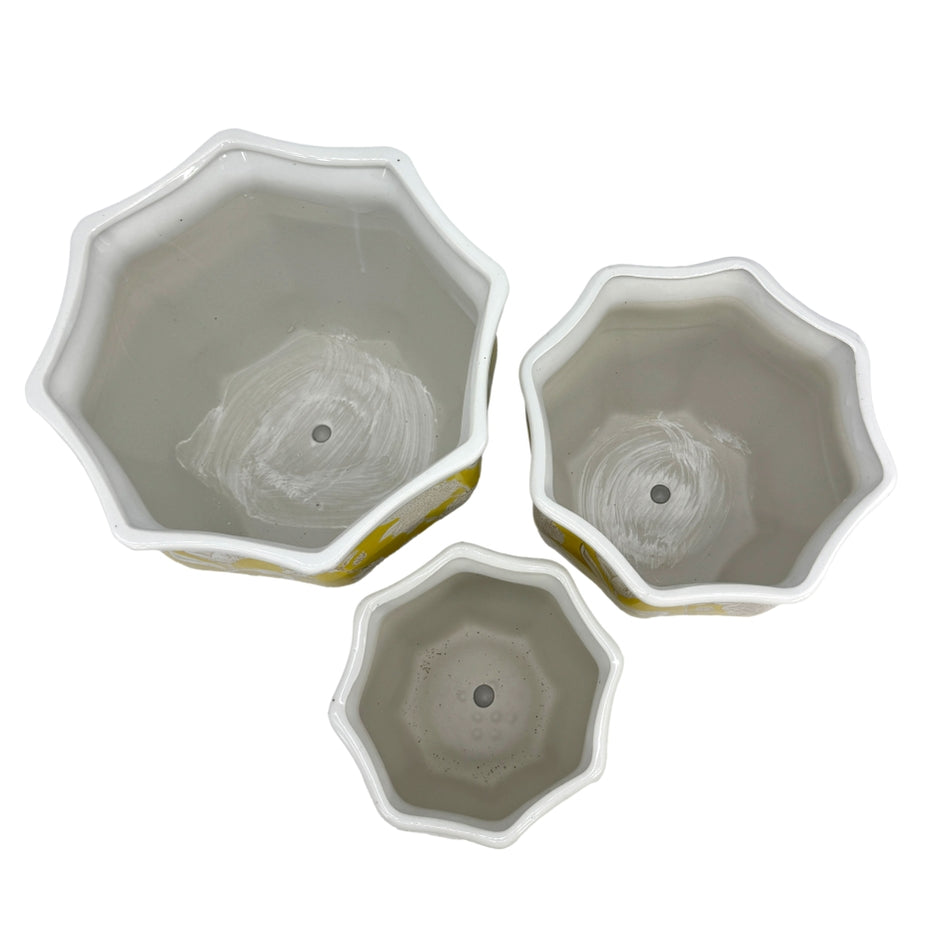 Top-down view of three yellow and white fluted ceramic chinoiserie planter pots in varying sizes.
