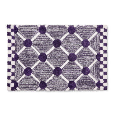 Handmade cotton bath rug with a lattice and dot geometric pattern in neutral tones.