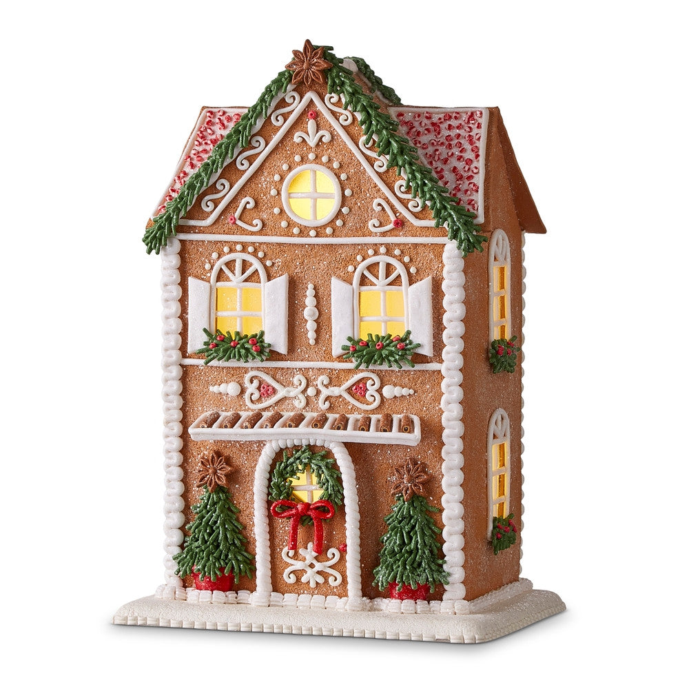 13-inch lighted gingerbread house with white icing details, green trees, and a red bow on the door.