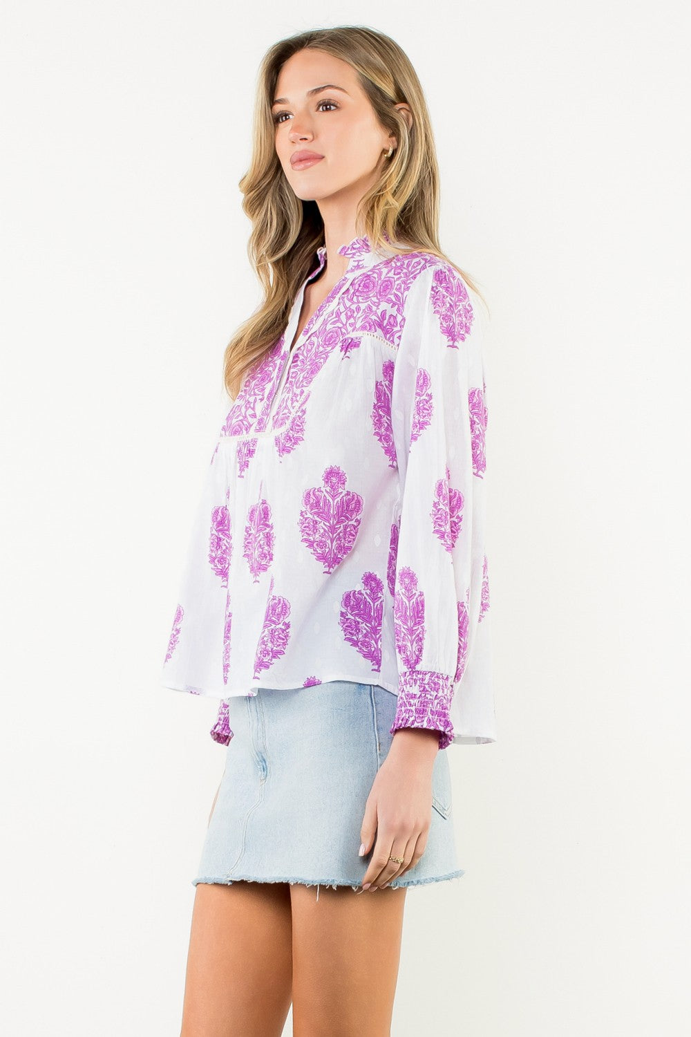 Woman wearing the Amy Long Sleeve Flower Print Top in white with purple floral patterns.
