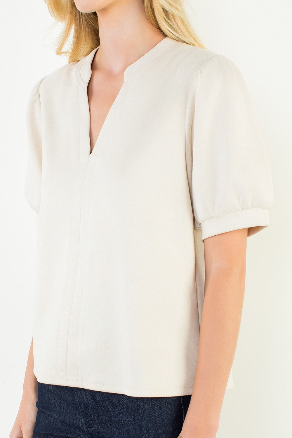 Woman wearing a cream-colored Juliana Soft Suede V-Neck Top with short puff sleeves.