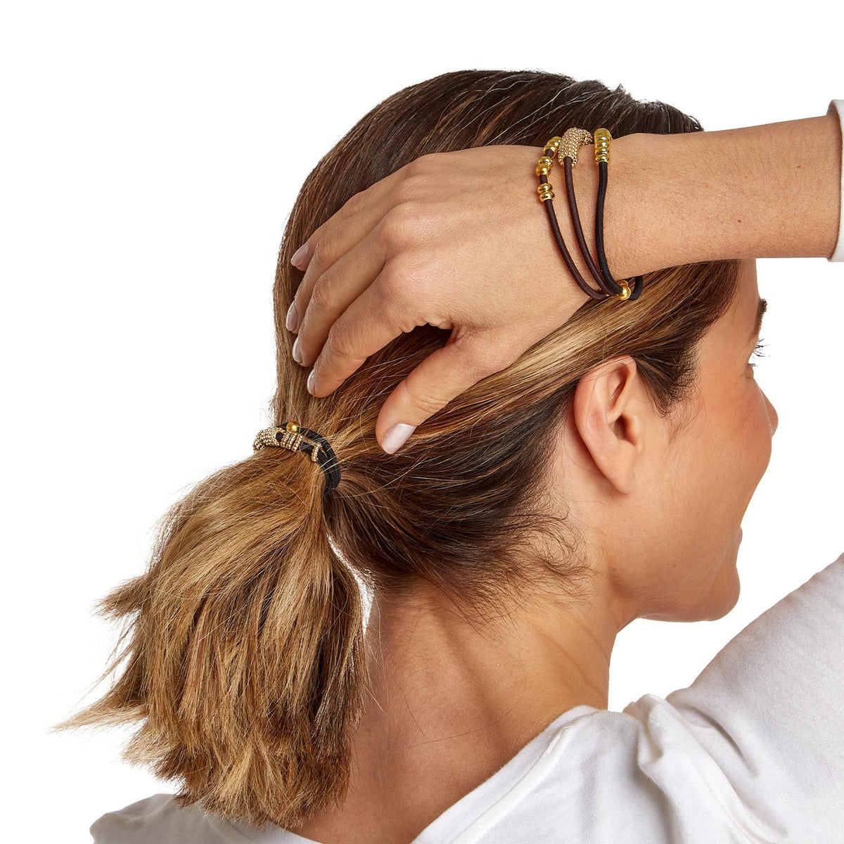 Woman wearing brown elastic hair tie bracelets with gold beads on her wrist and in her hair.