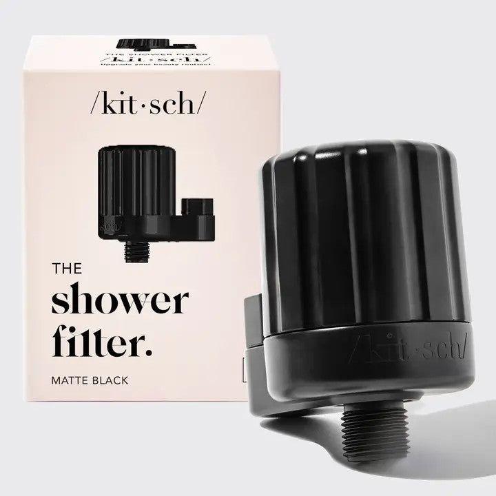 Matte black Kitsch shower filter next to its product box on a light grey background.