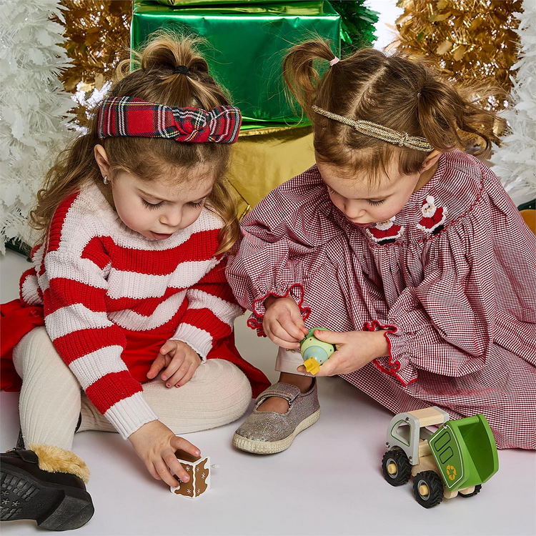 Two children playing with a wooden wind-up spinning toy and a green toy truck.