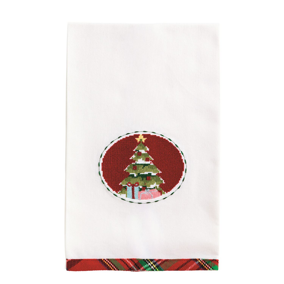 White cotton hand towel with a needlepoint Christmas tree in a red oval and a tartan plaid hem.