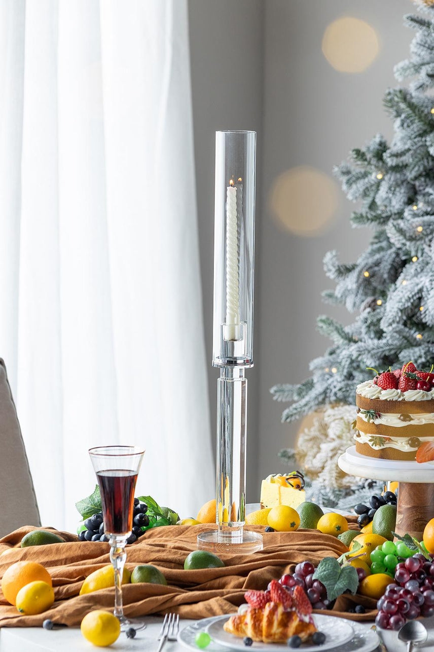 24-inch clear glass candle holder with a lit white spiral candle on a festive dining table.