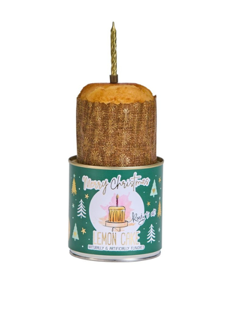 Cancake lemon cake in a green Christmas-themed tin with a gold candle on top.