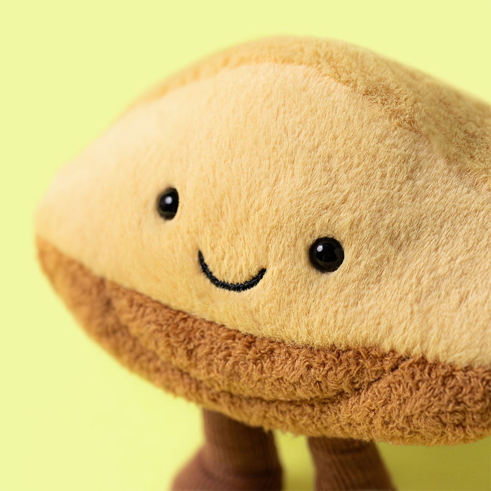 Close-up of Amuseables Margaux Madeleine plush toy with a smiling face and cordy legs.