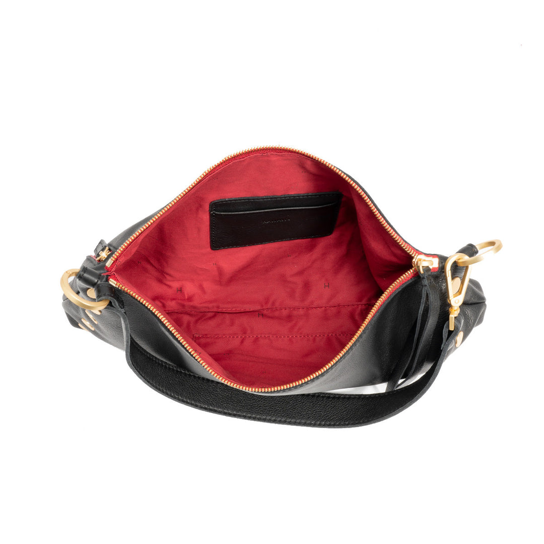 Black pebble leather Kyle Med crossbody bag with brushed gold hardware, red twill lining, and a front zip closure.