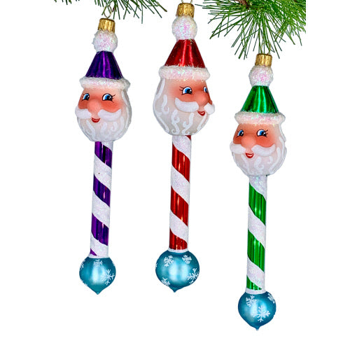 Three glass Santa Claus Christmas ornaments with candy cane bodies and snowflake bases in purple, red, and green.