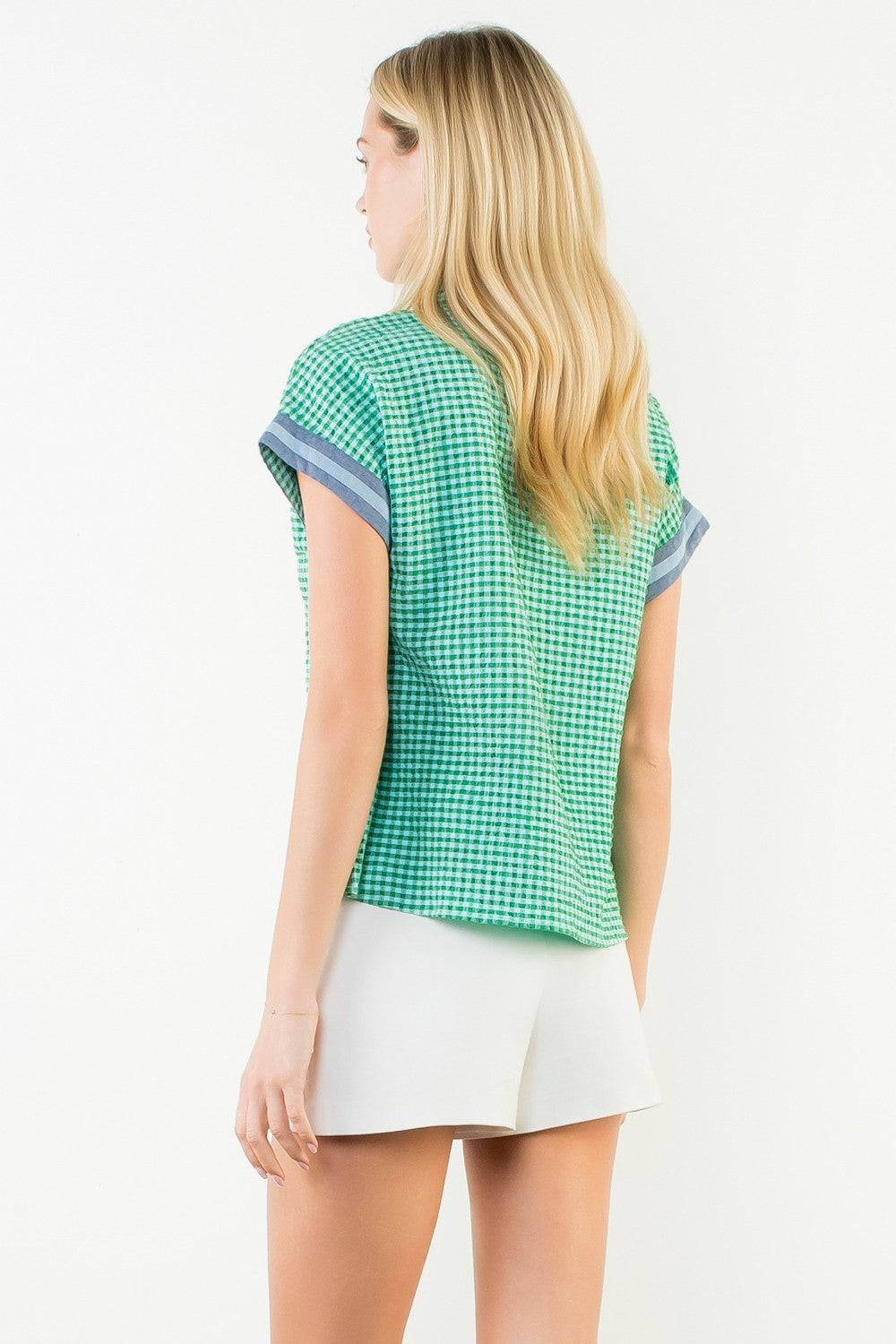 Back view of a woman wearing the Ariana green and white gingham short sleeve top with white shorts.