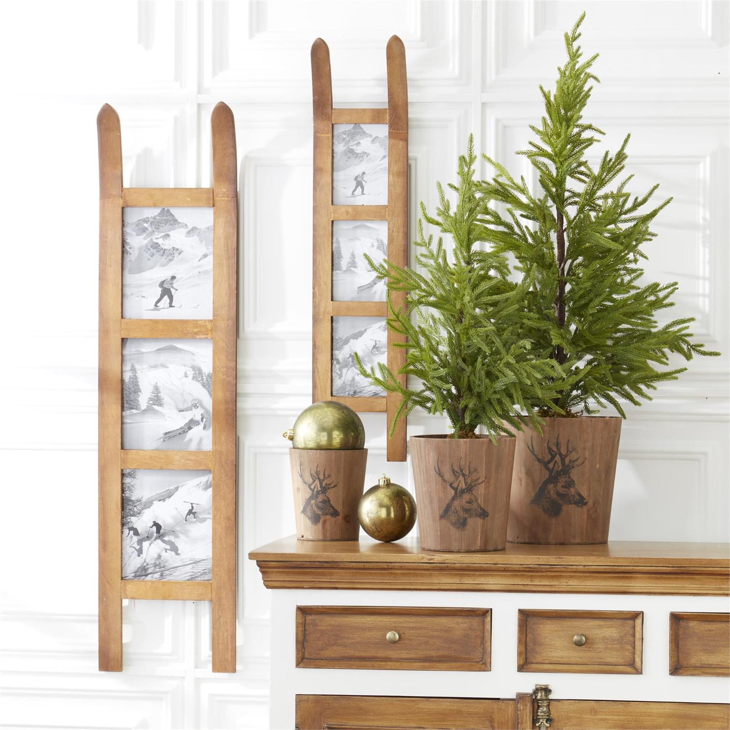 Two wooden sled-shaped wall hanging photo frames in different sizes next to holiday decor.
