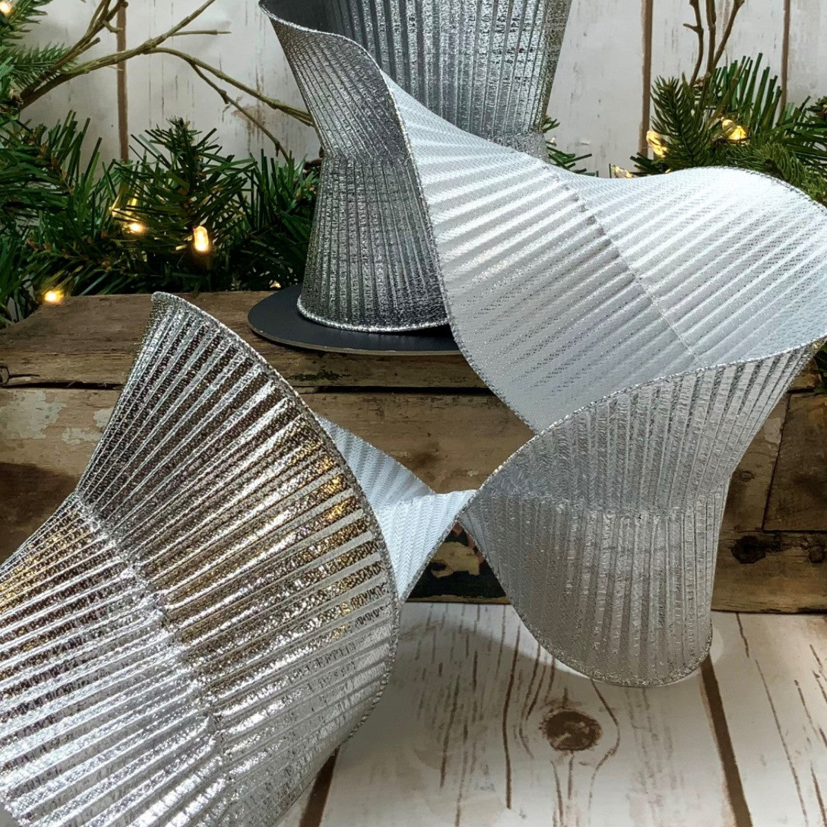 5-inch wide silver fluted lame ribbon with a metallic pleated texture draped on a wooden surface.
