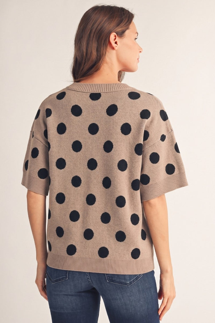 Back view of a woman wearing the Emily Polka Dot Comry Sweater Top in taupe with black polka dots.