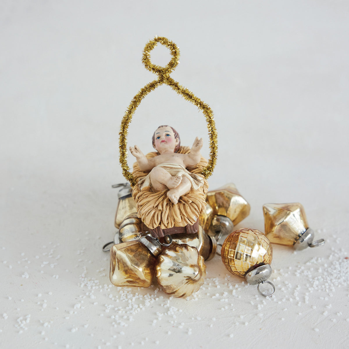 Resin vintage reproduction Baby Jesus ornament in a manger with a gold tinsel halo.