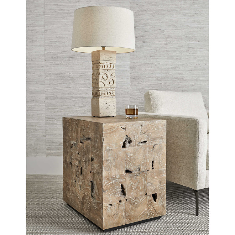 A rustic wooden cube end table with a textured stone lamp and a glass of whiskey.