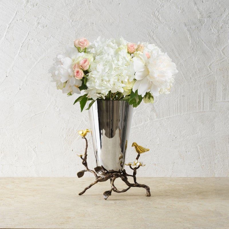 Small stainless steel vase with oxidized brass accents featuring white four-petaled enamel flowers symbolizing unity.