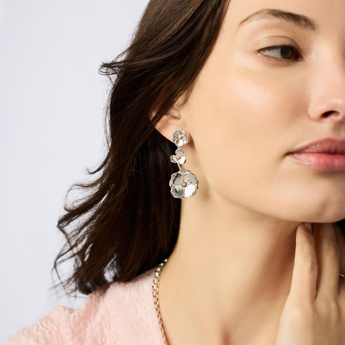 A woman wearing the Bloom Tier Earring in silver, featuring three tiered floral charms.