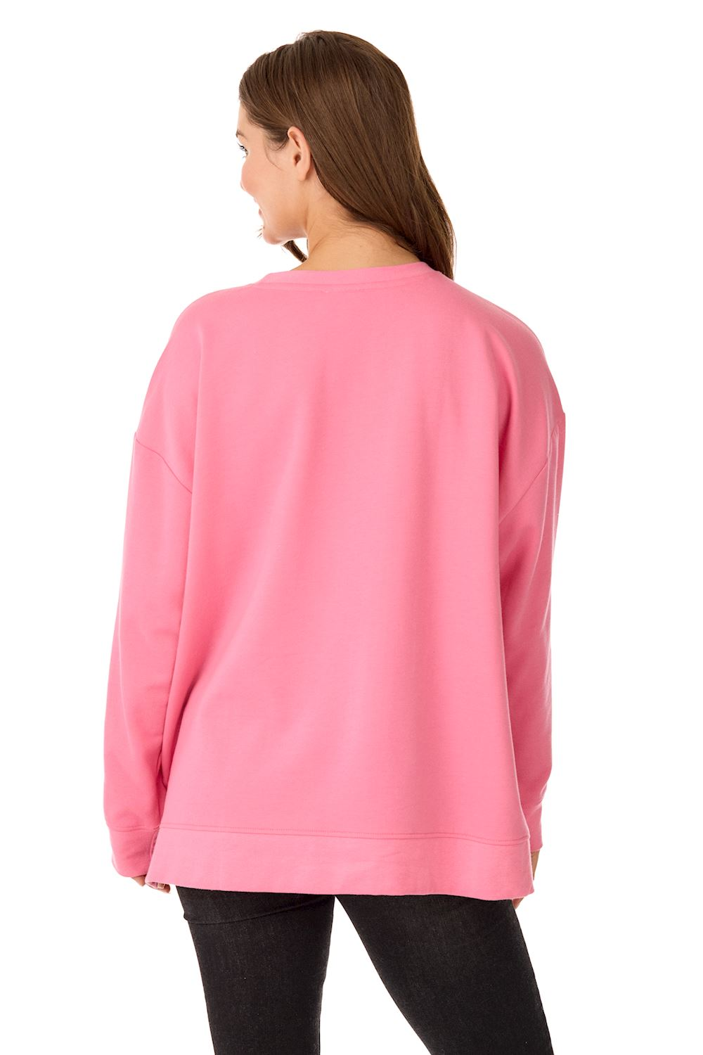 Back view of a woman wearing a pink oversized Holiday Bow Sparkle Sweatshirt and black pants.