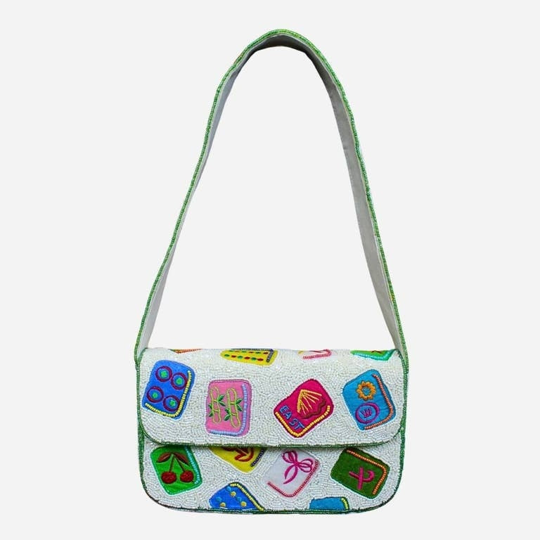 White beaded shoulder bag with colorful mahjong tile motifs and a green beaded strap.