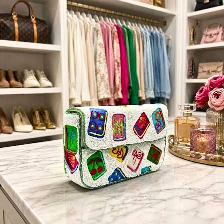 White beaded shoulder bag with colorful mahjong tile motifs on a marble surface in a closet.