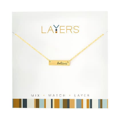Gold layered necklace featuring a 'Believe' tag pendant with mixed chain lengths.