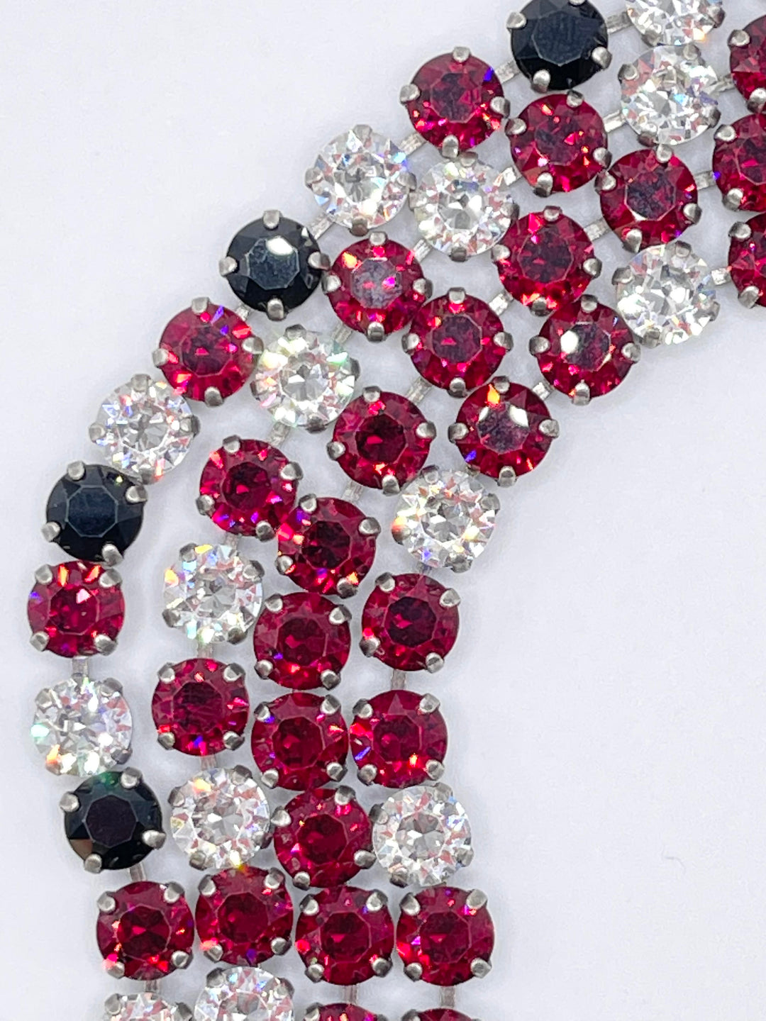 Close-up of the Rome Classic Bracelet featuring rows of deep red, black, and clear round stones.