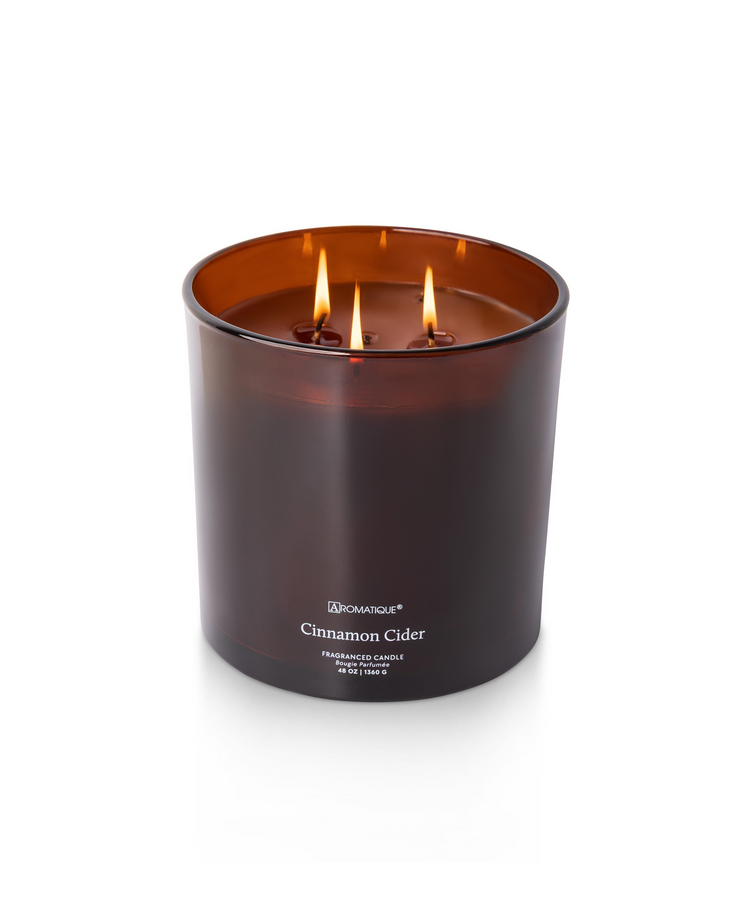 Cinnamon Cider 48 oz three-wick candle in a large amber glass vessel with lit flames.