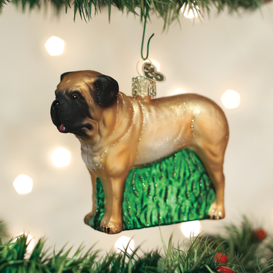 Glass English Mastiff Christmas ornament with a tan coat and black mask, standing on green grass.