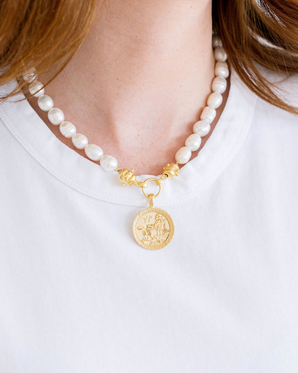 A woman wearing the Blue Willow Pearl Necklace with a gold coin pendant and freshwater pearls.
