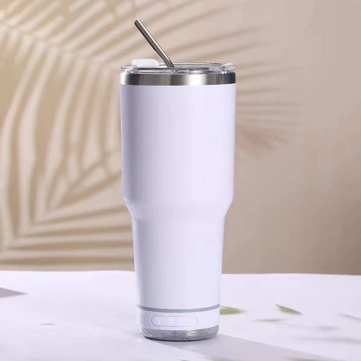 White 30 oz stainless steel tumbler with a built-in Bluetooth speaker base and a metal straw.