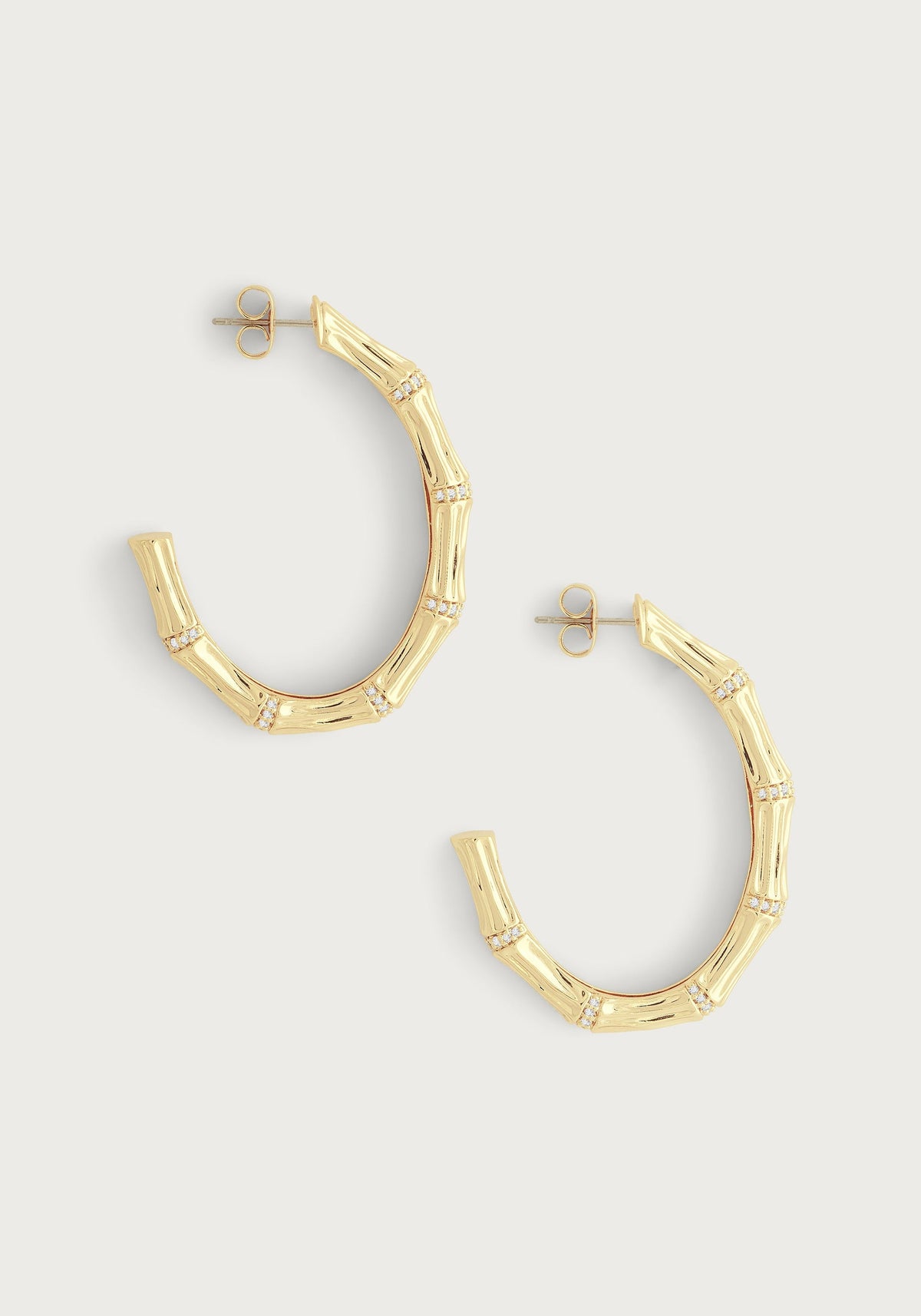 A pair of 18K gold-plated bamboo-shaped oval hoop earrings with crystal pavé accents.