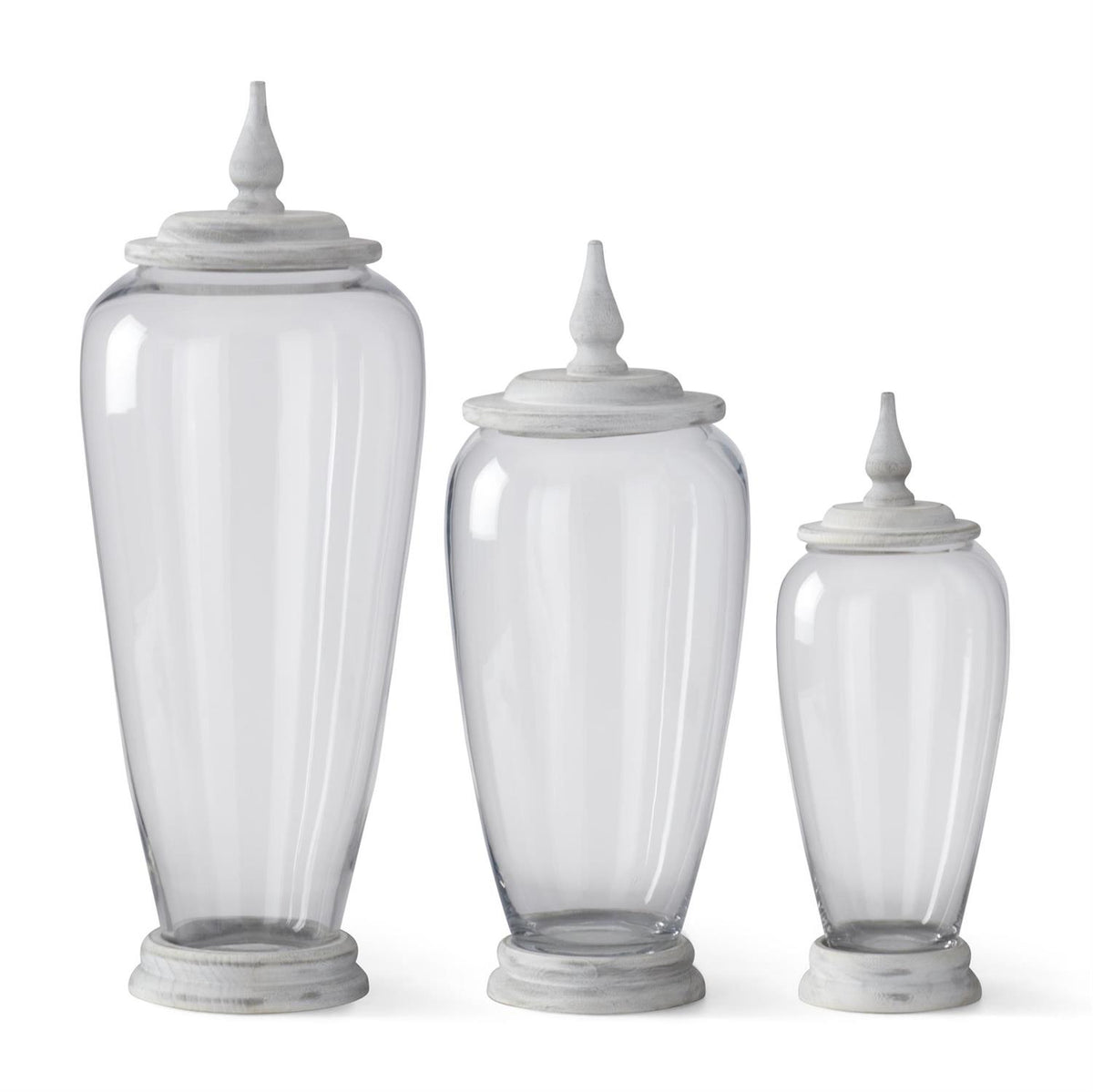 Set of three clear glass jars in varying sizes with white-washed wood bases and matching finial lids