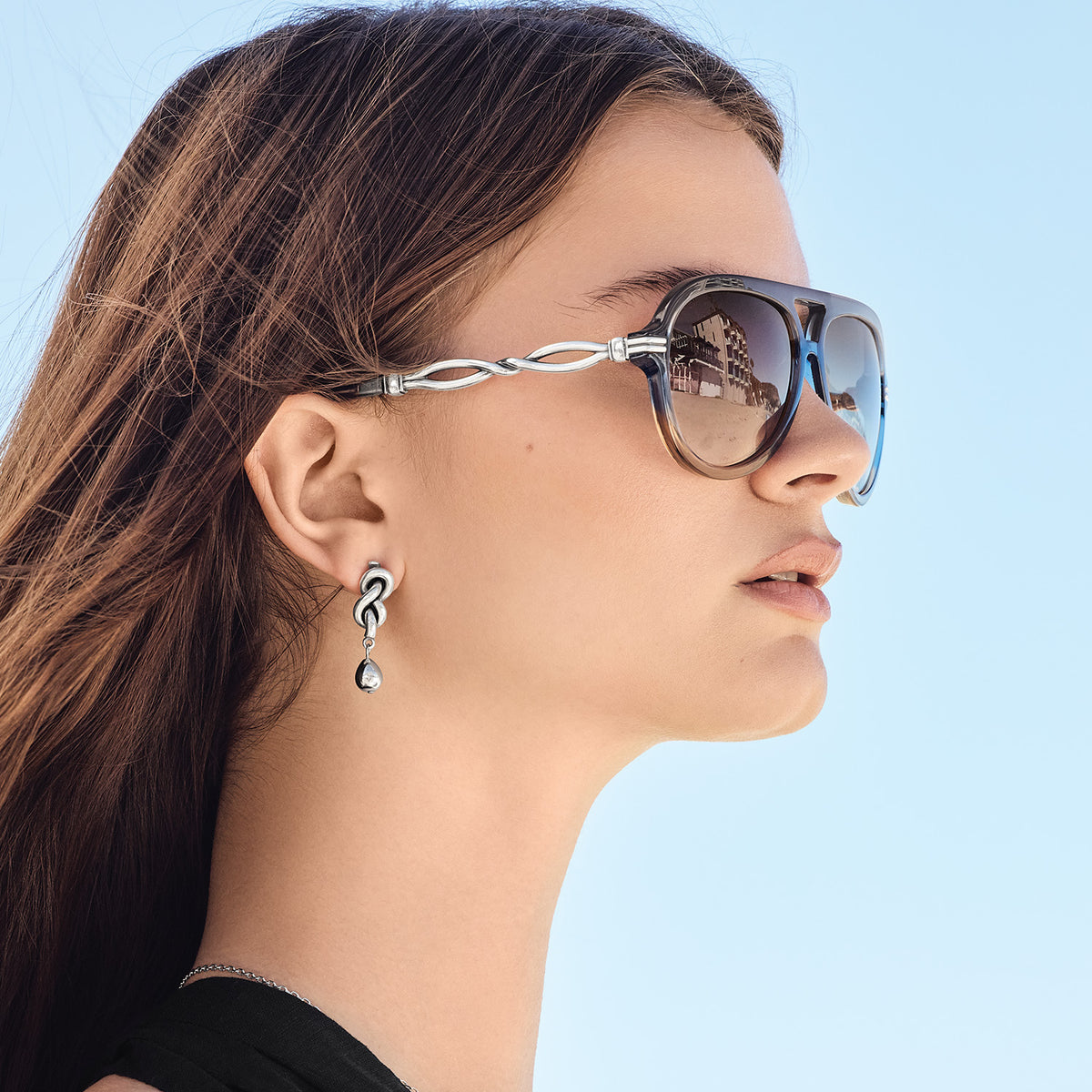 Woman wearing blue Interlok Twist Aviator Sunglasses with silver-plated twisted temple details.
