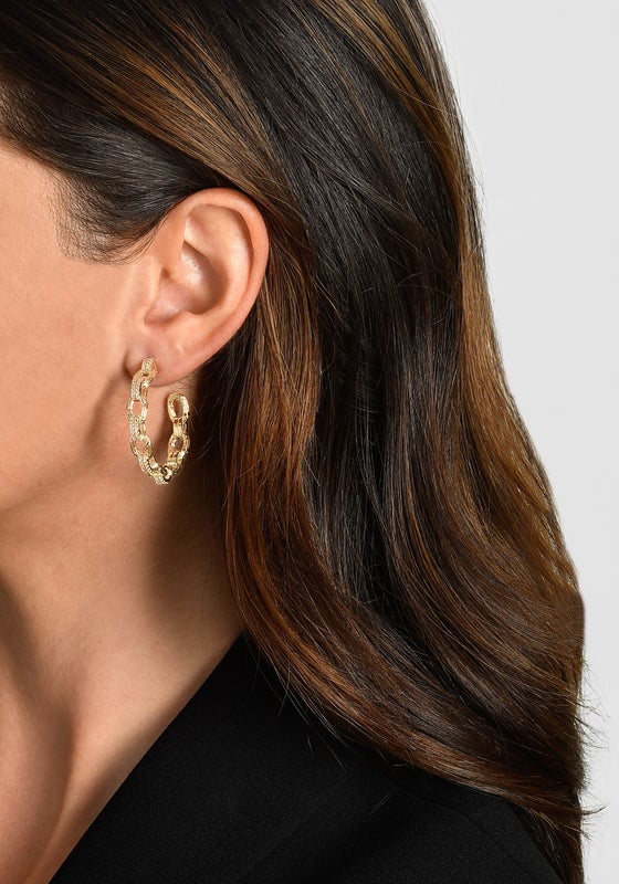 Woman wearing gold-plated chain hoop earrings with twig texture and crystal accents.
