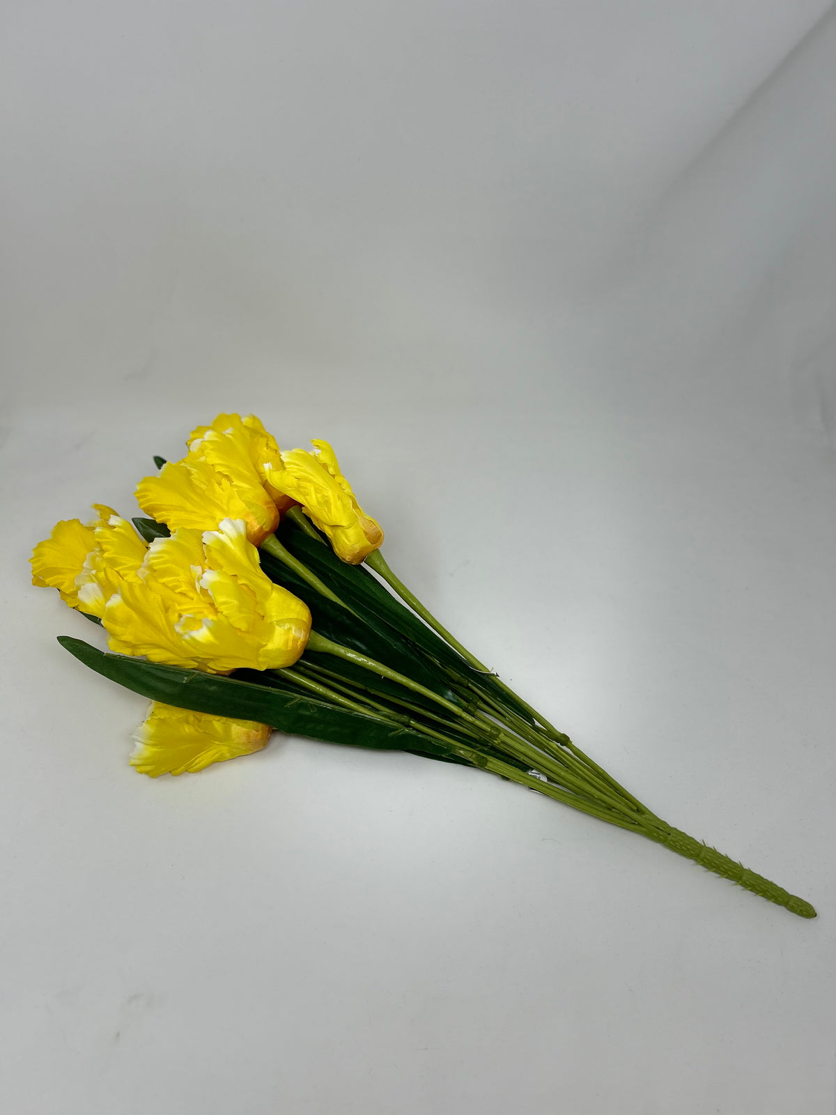A bouquet of 12 artificial yellow tulips with green leaves and stems.
