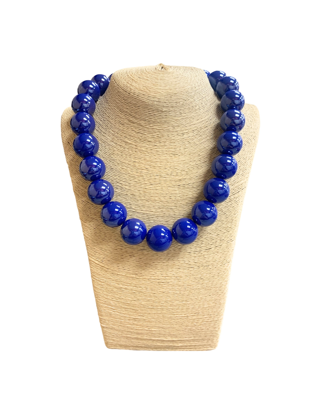 Short necklace with large, glossy blue glass ball beads on a beige textured jewelry bust.