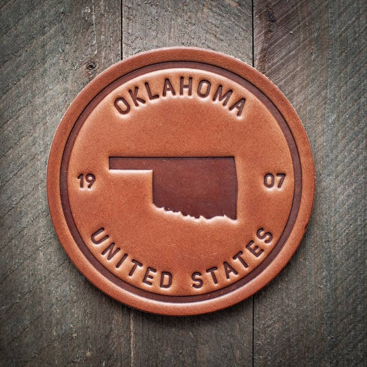 Square leather coaster featuring a black Oklahoma state silhouette on tan background.