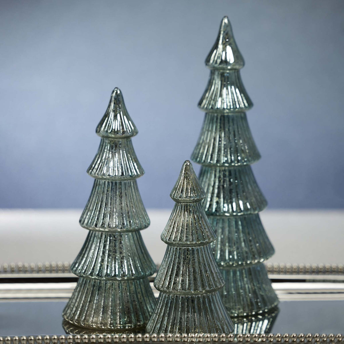 Blue glass ribbed antique tree with integrated LED lights on a tabletop.