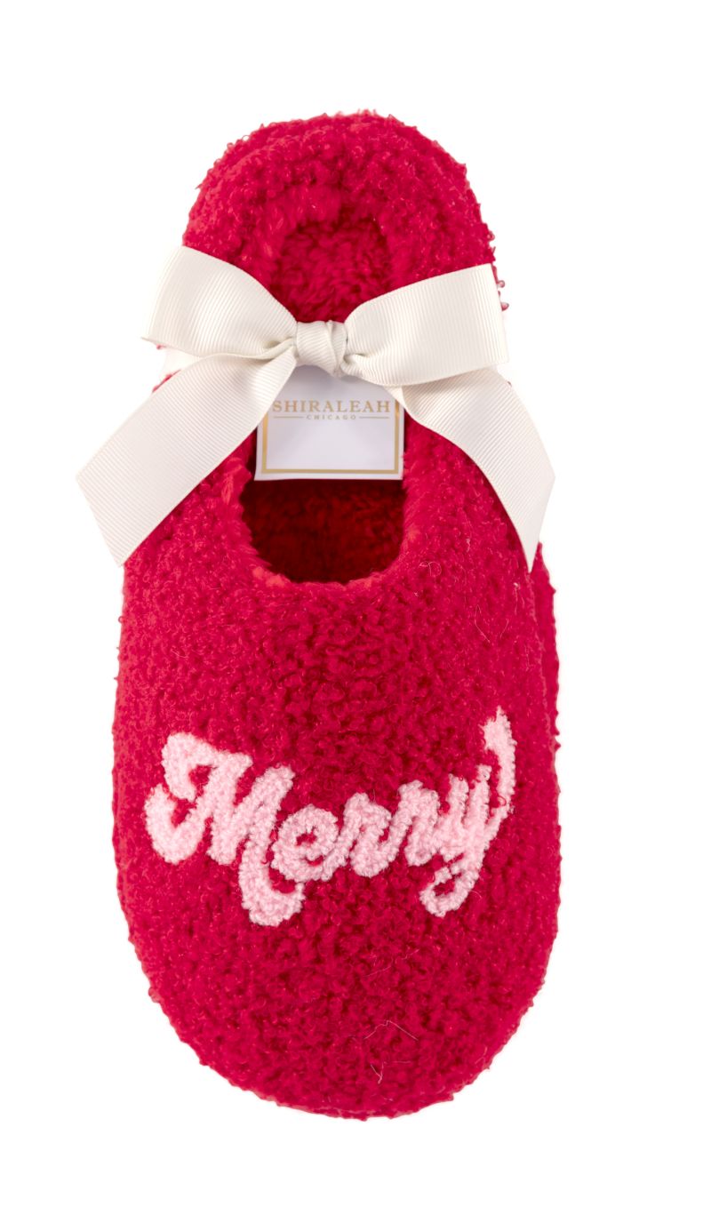 Red fuzzy slippers with "Merry" embroidered in pink and white, tied with a cream ribbon.