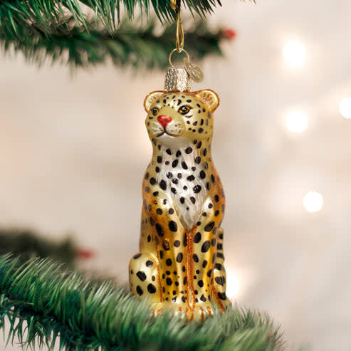 Leopard ornament figurine in tan with black spots on a natural wood base.
