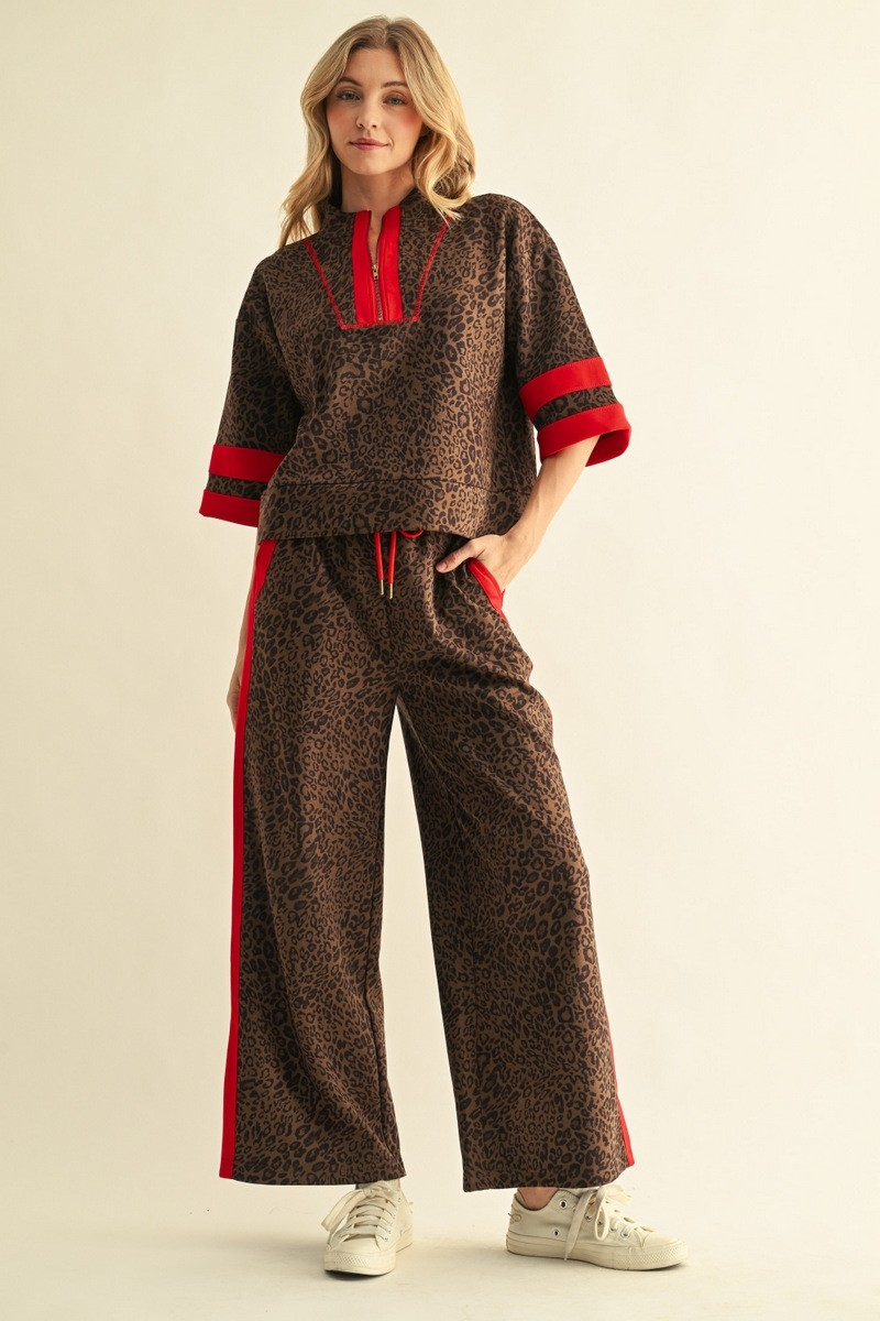 Woman wearing a brown leopard print faux suede top with red contrast trim and matching wide-leg pants