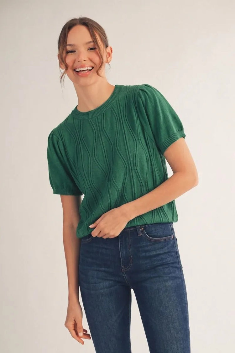 Woman wearing a green Miranda short sleeve lightweight sweater with a textured wave pattern.