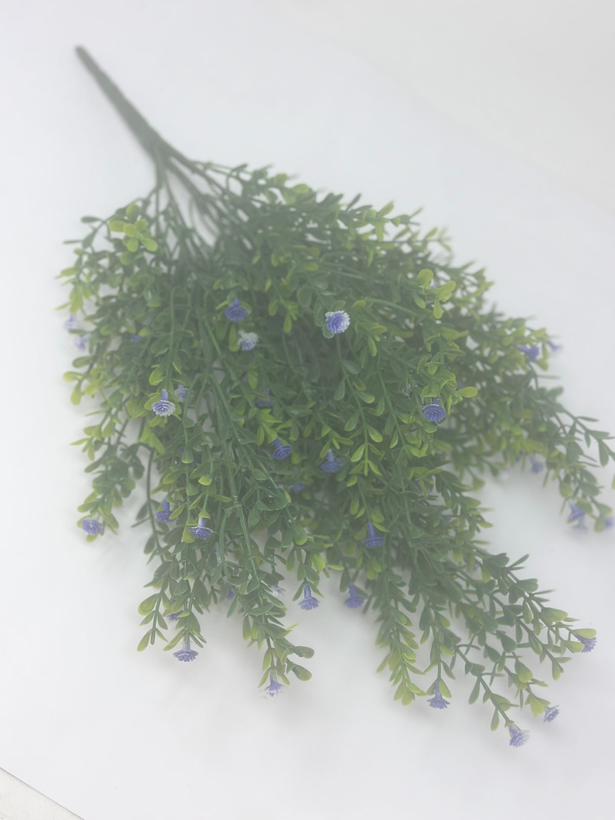 A green artificial gypso bush with small purple flowers on a white background.