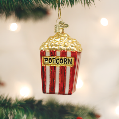 Glass popcorn bucket Christmas ornament with red and white stripes hanging on a tree branch.