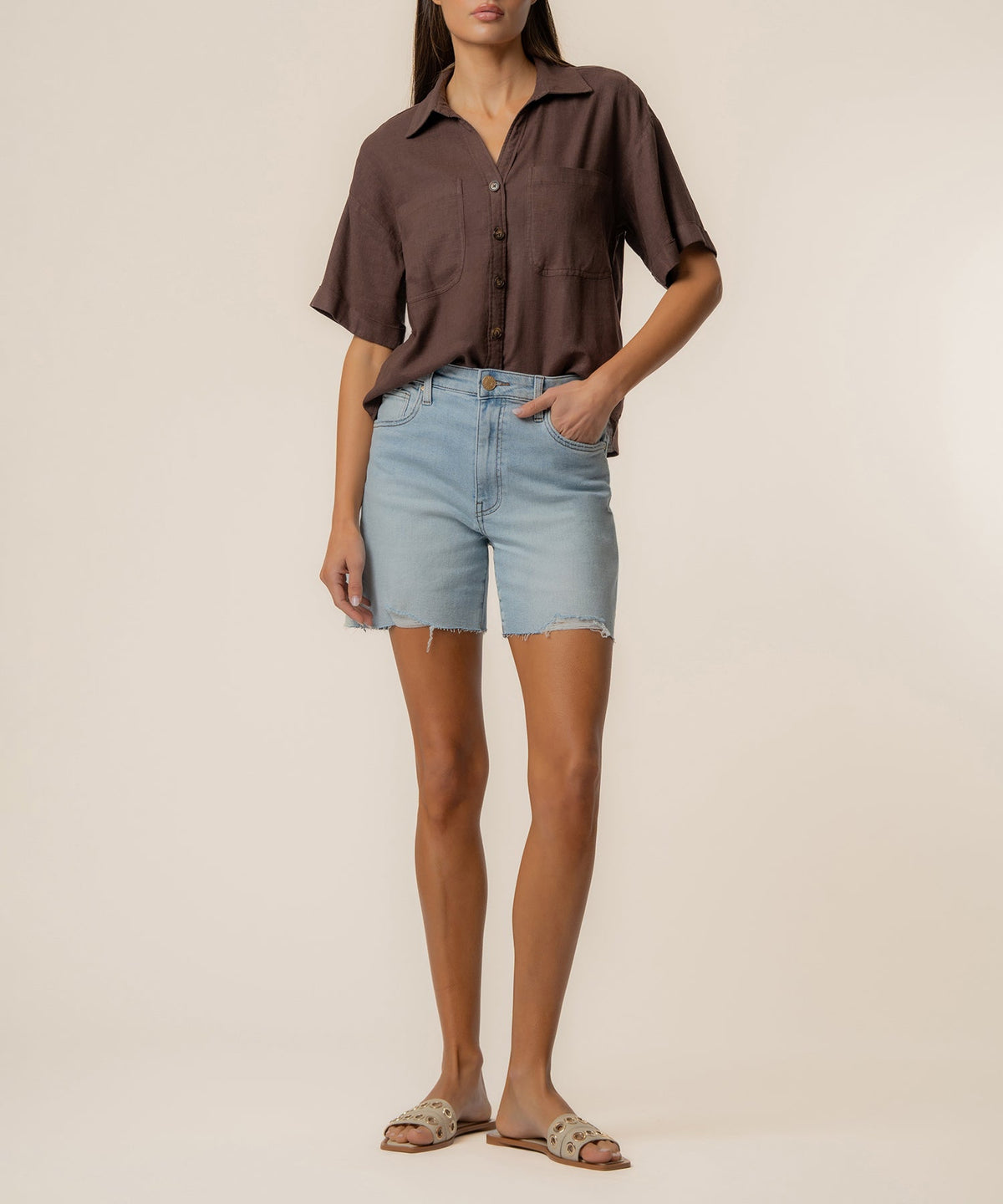 Woman wearing a brown Brianna Linen Boxy Shirt with light wash denim shorts and sandals.