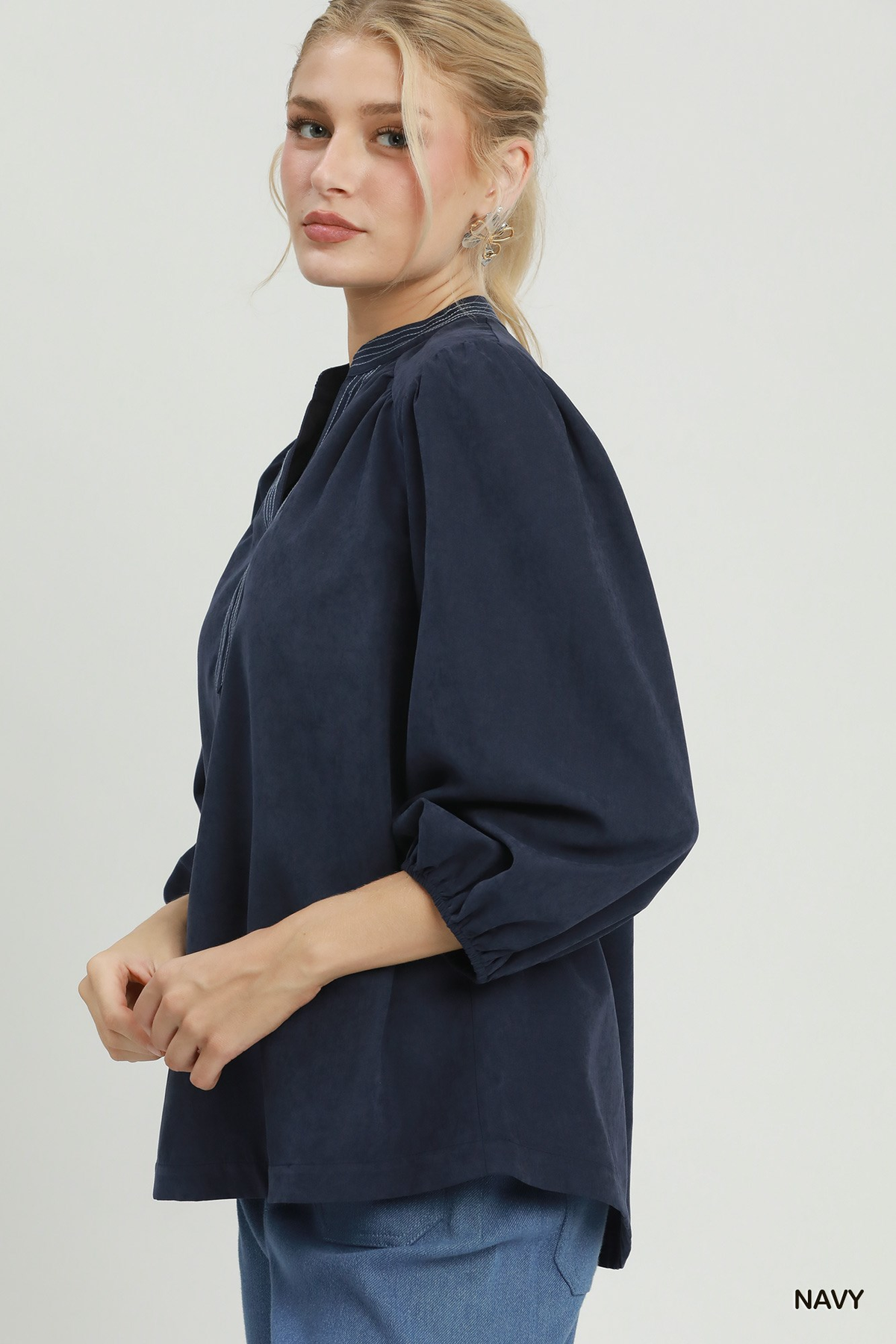 Woman wearing a navy Clara Sueded Split Neck Blouse with contrast stitching and balloon sleeves.