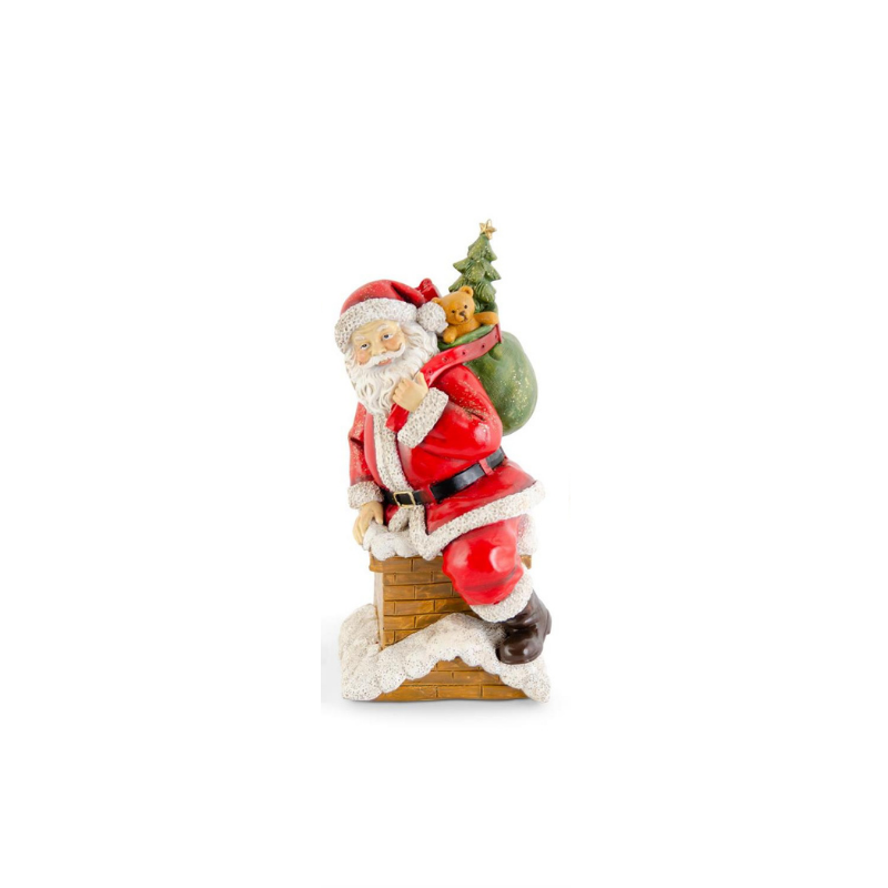 Glittered resin Santa figurine sitting on a snow-covered chimney with a toy sack and teddy bear.
