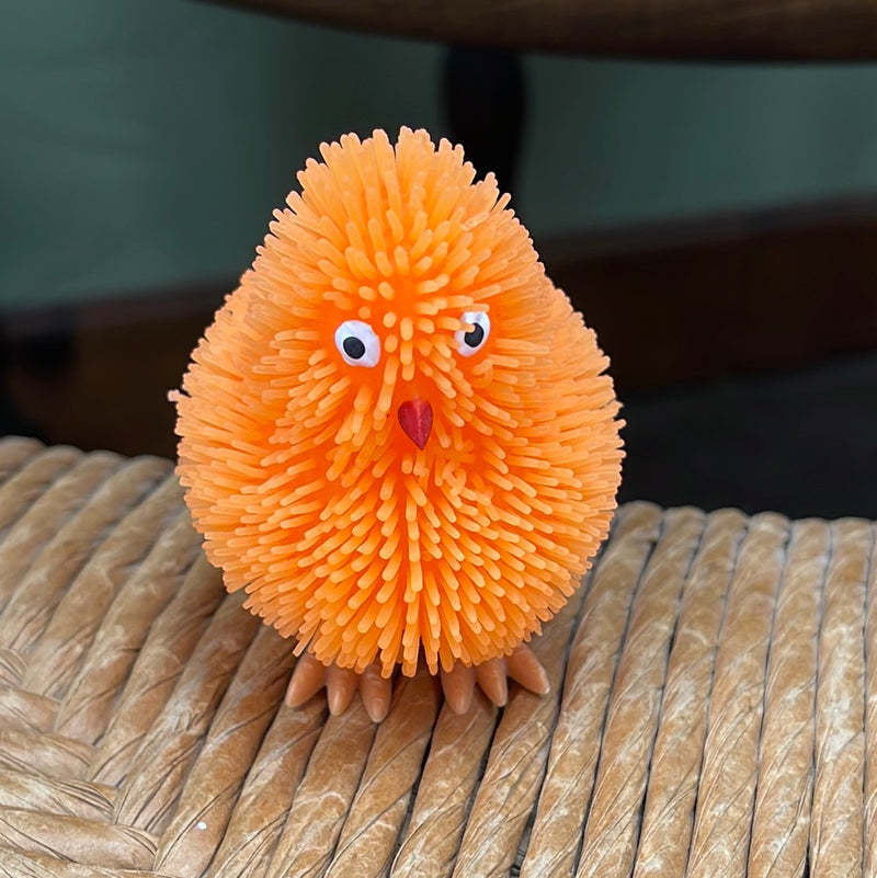 Orange plastic toy chick with fringe that lights up when tossed.