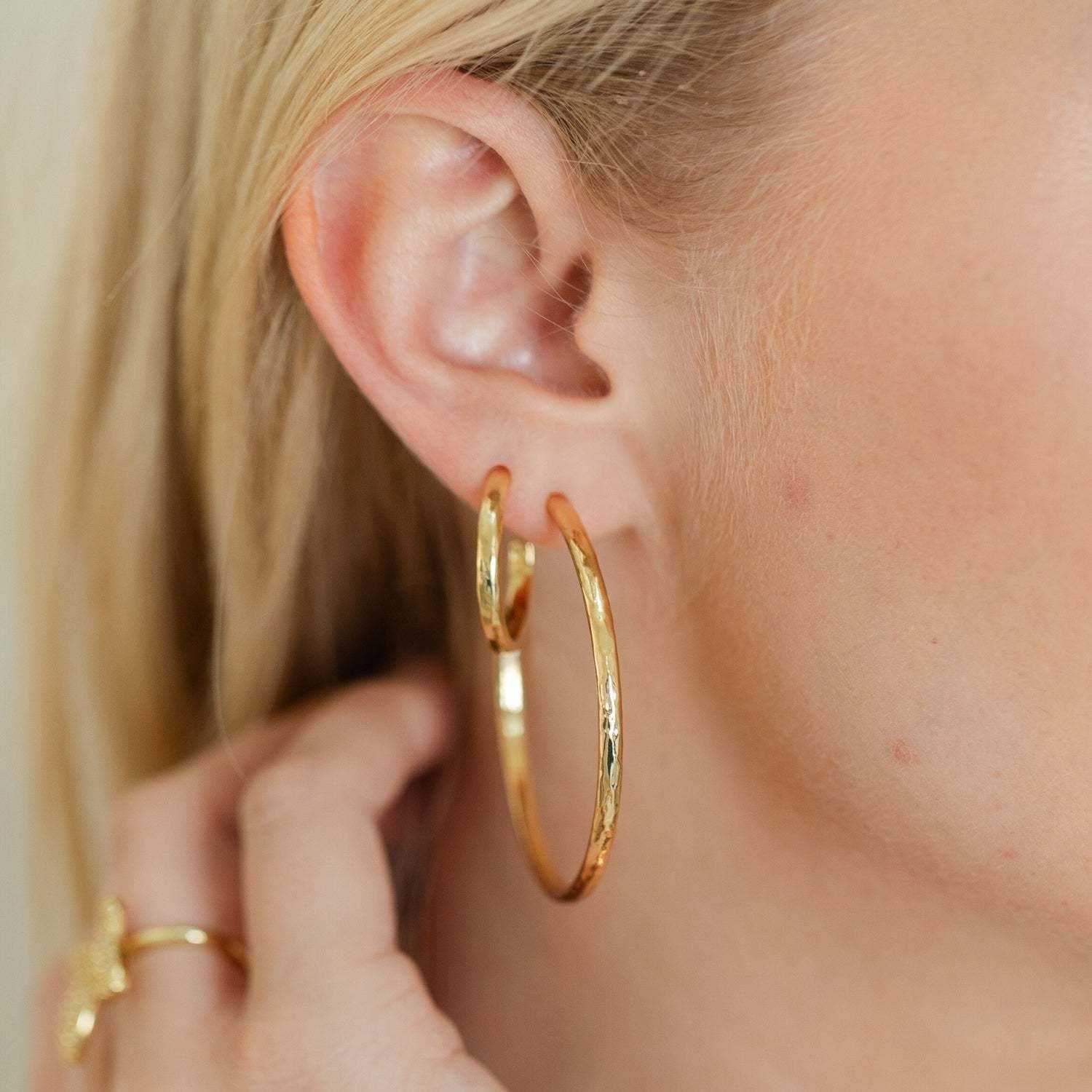 Large delicate hoop earrings with a lightly textured finish in gold.